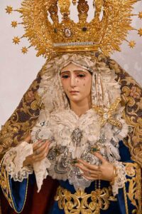 la venerada imagen luce saya de terciopelo azul bordada en oro, y toca de sobremanto bordada en oro sobre malla
