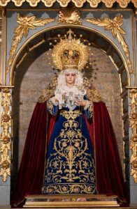 la venerada imagen luce saya de terciopelo azul bordada en oro, manto rojo en terciopelo liso y toca de sobremanto bordada en oro sobre malla